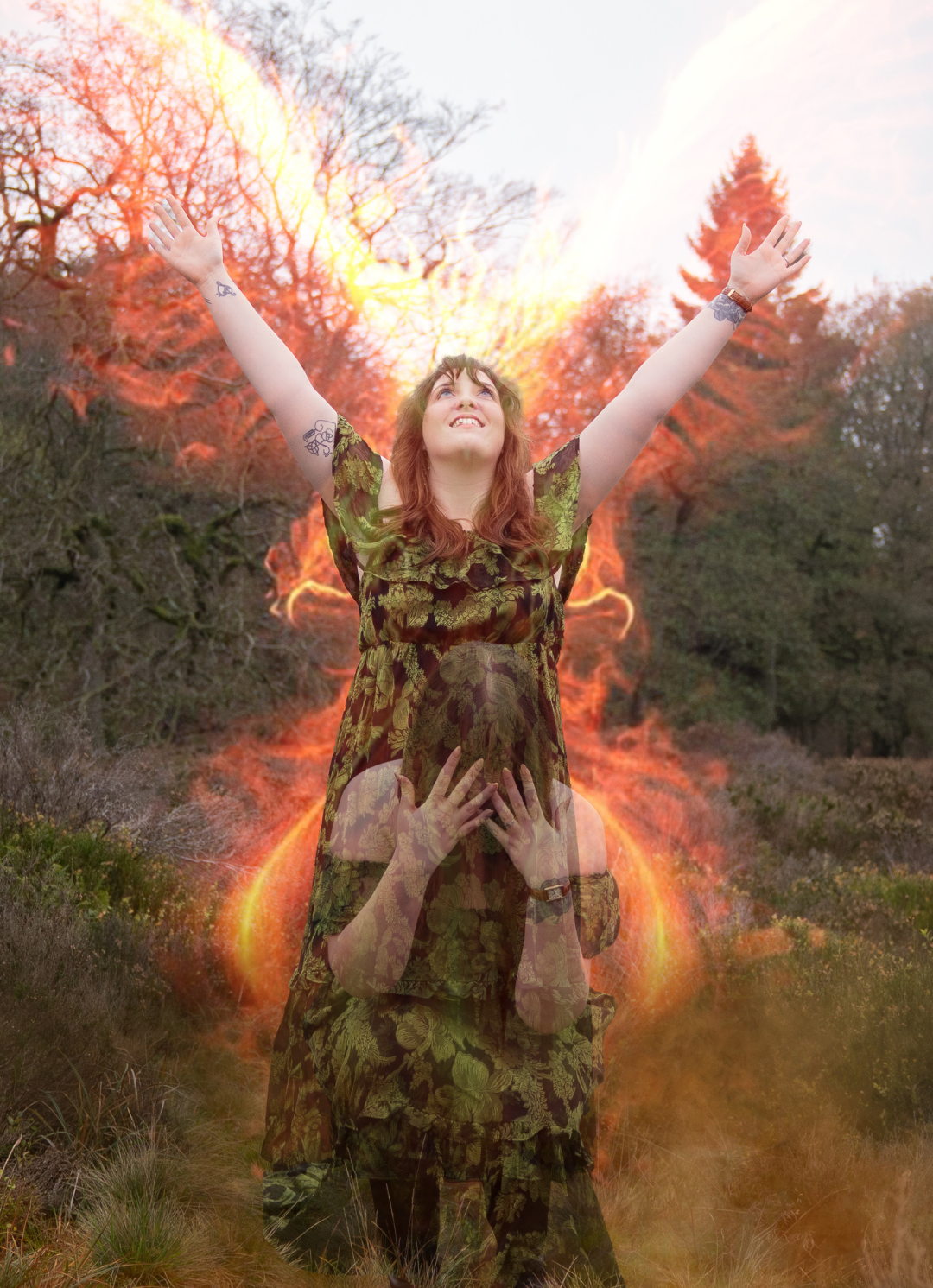 Nord-Essence founder Rhiannon stands in a forest clearing wearing an off-the-shoulder dress with a green and black leafy pattern. Her long brown hair blends with the surrounding foliage as she gazes softly to the side, enveloped by tall grasses and dense trees in the muted light of late afternoon — a moment of quiet harmony with nature.